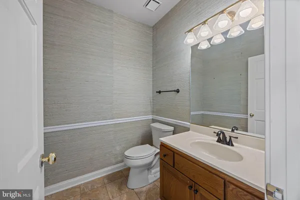 a bathroom with a sink vanity granite toilet and a mirror