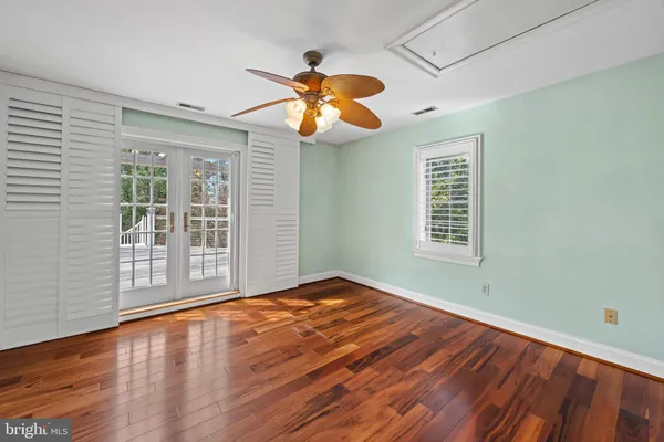 a view of empty room with wooden floor and fan