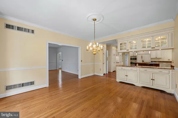 a large kitchen with cabinets wooden floor and a chandelier
