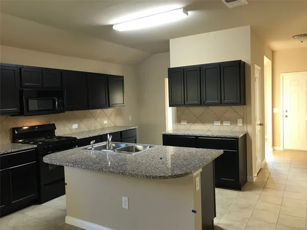 a kitchen with granite countertop a sink a stove and cabinets