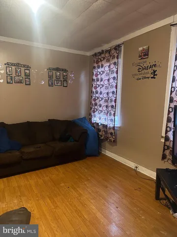 a living room with a couch and a bookshelf with wooden floor