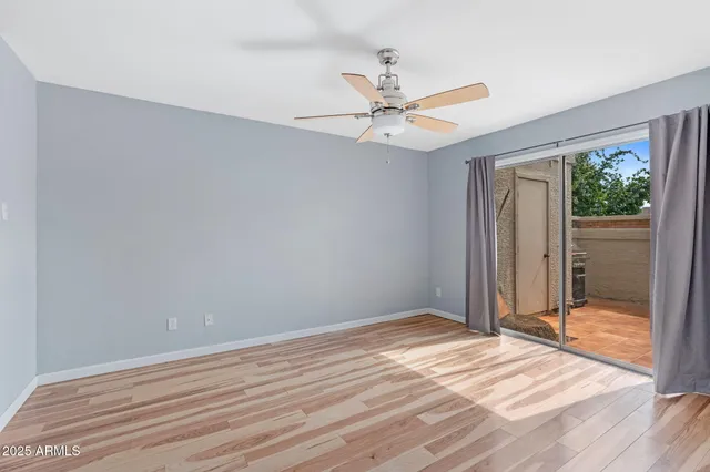 a view of empty room with wooden floor and fan