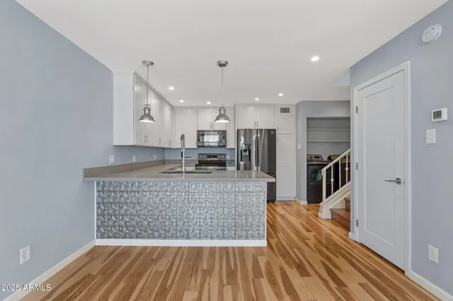 a kitchen with kitchen island a counter top space a sink stainless steel appliances and cabinets