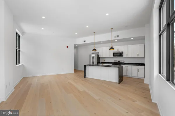 a large white kitchen with stainless steel appliances granite countertop a stove a sink dishwasher and a refrigerator with wooden floor