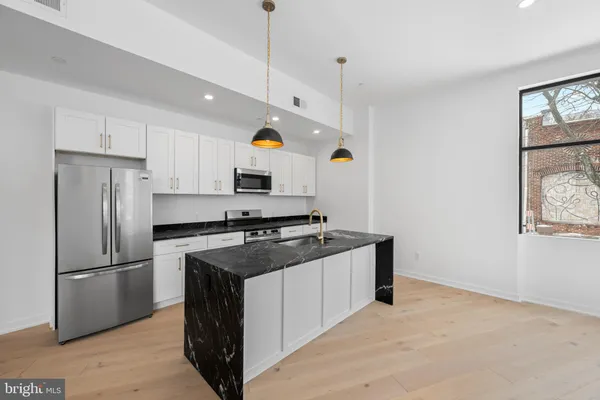 a kitchen with kitchen island a counter space a stove a refrigerator and a window