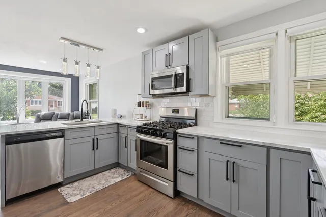 a kitchen with stainless steel appliances granite countertop a stove a sink and a microwave