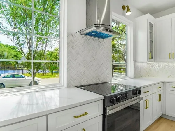 a view of an empty room and kitchen with wooden floor