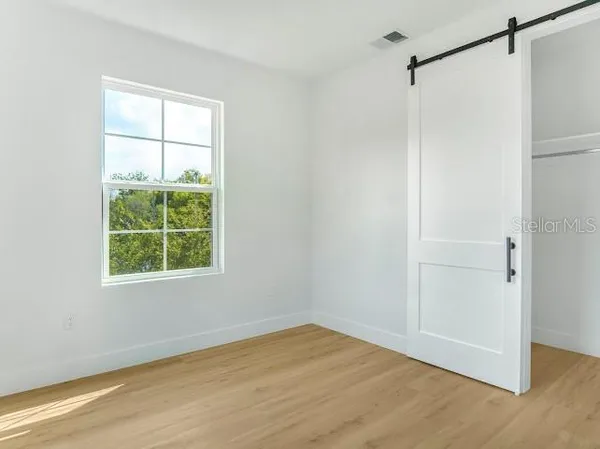 a view of an empty room with wooden floor and a window