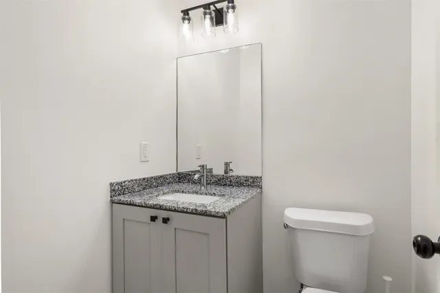 a bathroom with a granite countertop sink and a toilet