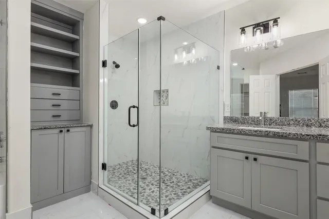 a bathroom with a granite countertop sink a mirror and shower