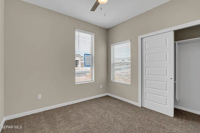 an empty room with ceiling fan and window