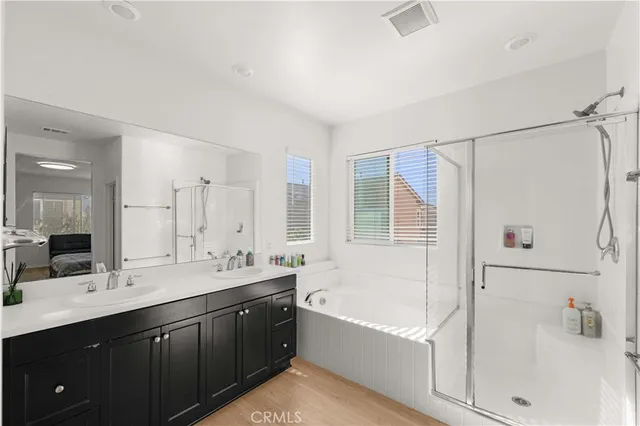 a bathroom with a tub sink double vanity granite tub shower and mirror
