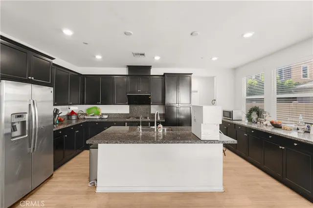 a large kitchen with kitchen island a large counter top stainless steel appliances and cabinets
