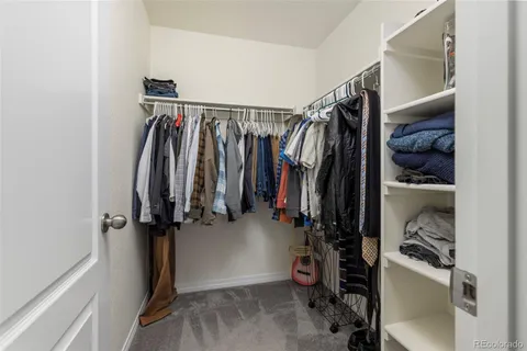 a view of walk in closet with clothes and shoes
