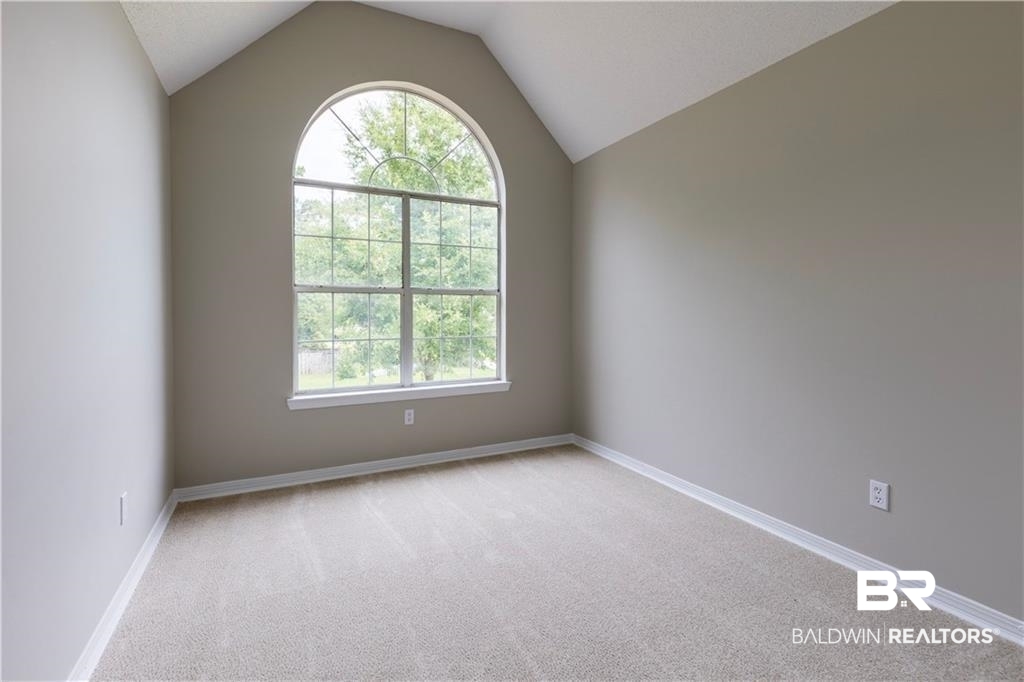 101 Lawson Road Daphne, AL 36526 - Photo 16 of 20 Vaulted ceiling room featuring a large arched window, light gray wall finishes, light-toned carpeting, and white baseboards