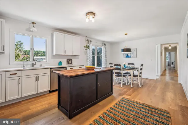 a kitchen with wooden cabinets a sink dishwasher a dining table and chairs with wooden floor