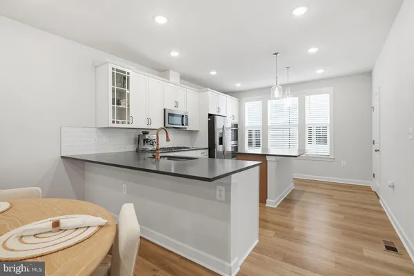 a kitchen with stainless steel appliances granite countertop a sink a stove a refrigerator cabinets and wooden floor