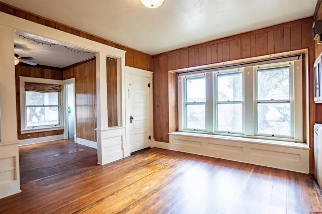 a view of an empty room with wooden floor and a window