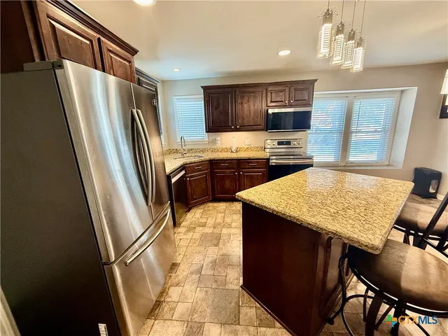 a kitchen with stainless steel appliances granite countertop a refrigerator a stove a sink dishwasher and a refrigerator with wooden floor