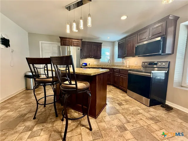 a kitchen with stainless steel appliances granite countertop a stove top oven a sink dishwasher and cabinets