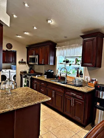 a kitchen with kitchen island granite countertop stainless steel appliances a sink a stove top oven a counter space and cabinets