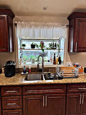 a kitchen with granite countertop a sink and wooden cabinets