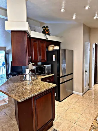 a kitchen with stainless steel appliances granite countertop a refrigerator a stove and a sink