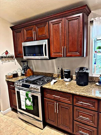 a kitchen with granite countertop a stove top oven microwave and cabinets