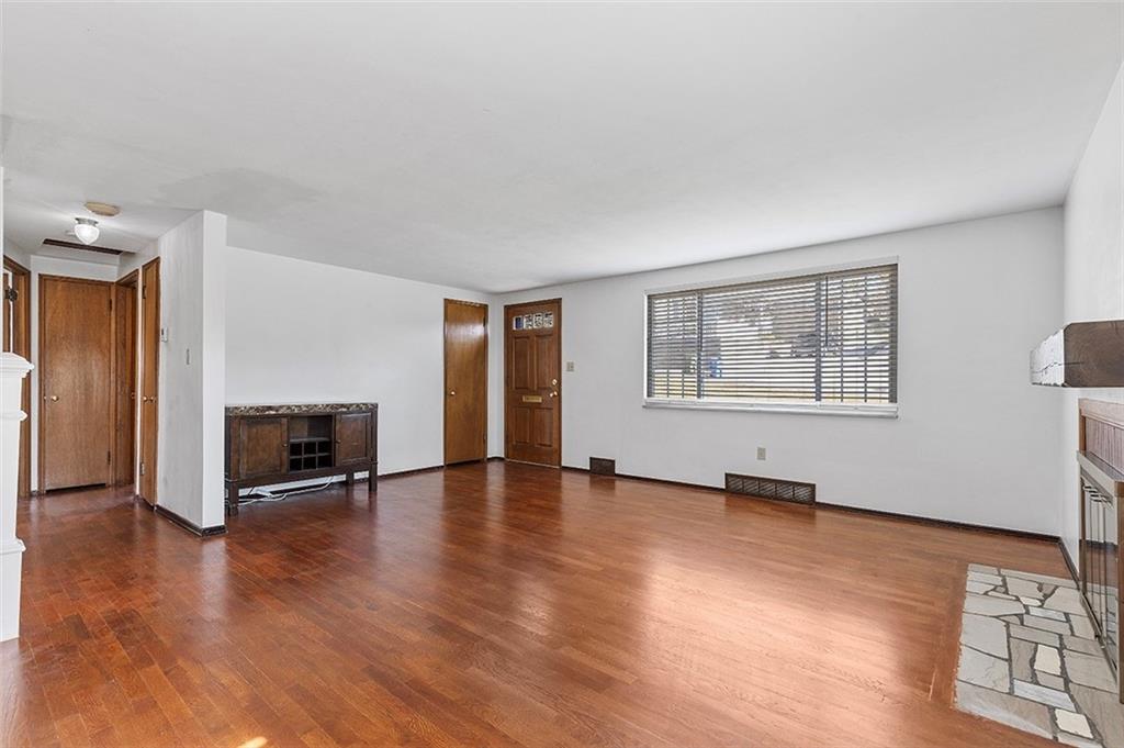 5018 Grove Road Pittsburgh, PA 15234 - Photo 11 of 41 an empty room with wooden floor fireplace and windows