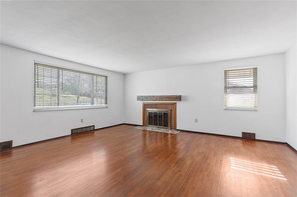 5018 Grove Road Pittsburgh, PA 15234 - Photo 12 of 41 an empty room with wooden floor fireplace and windows