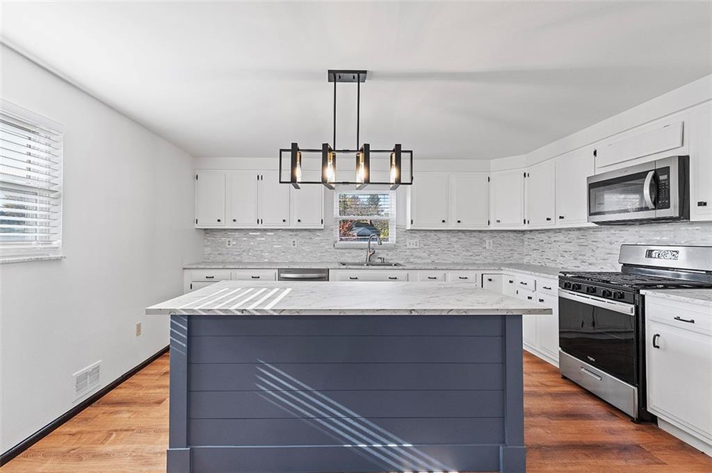 5018 Grove Road Pittsburgh, PA 15234 - Photo 17 of 41 a kitchen with kitchen island granite countertop stainless steel appliances a sink stove and cabinets