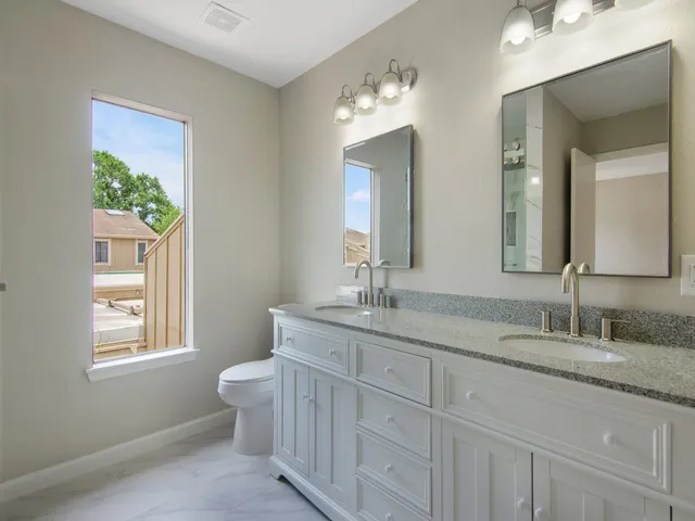 a bathroom with 2 sink toilet and a mirror