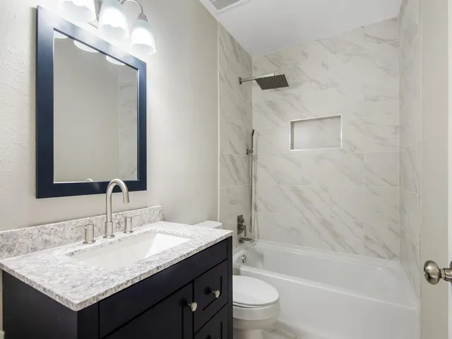 a bathroom with a granite countertop sink a toilet and shower
