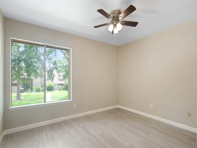 a view of an empty room with a window and a ceiling fan
