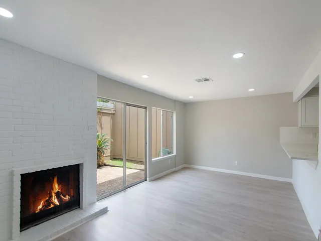 a view of an empty room with a fireplace and window