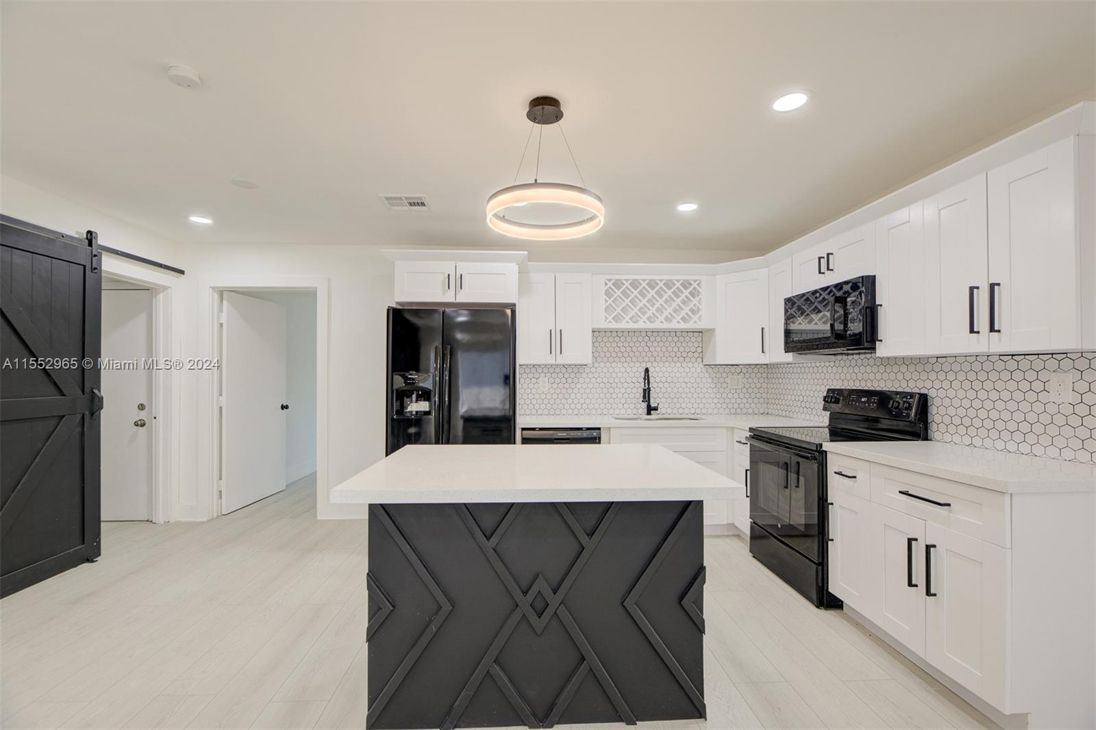 a large kitchen with stainless steel appliances kitchen island granite countertop a refrigerator a sink dishwasher and white cabinets with wooden floor