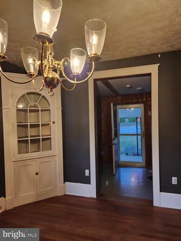 a view of a livingroom with a chandelier fan and wooden floor