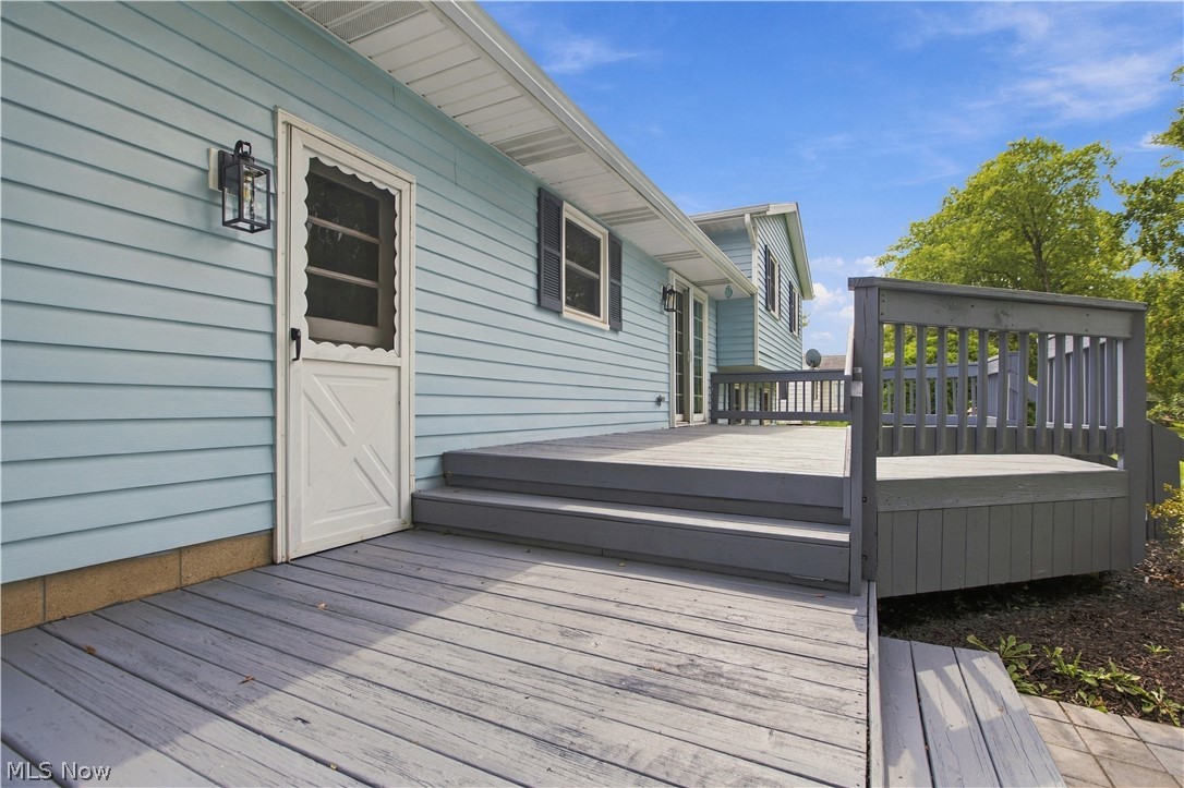 5972 Keller Road Akron, OH 44319 - Photo 28 of 29 Expansive multi-level wood decking with railing, light blue siding, exterior wall lantern, white screen door, and dark shutters