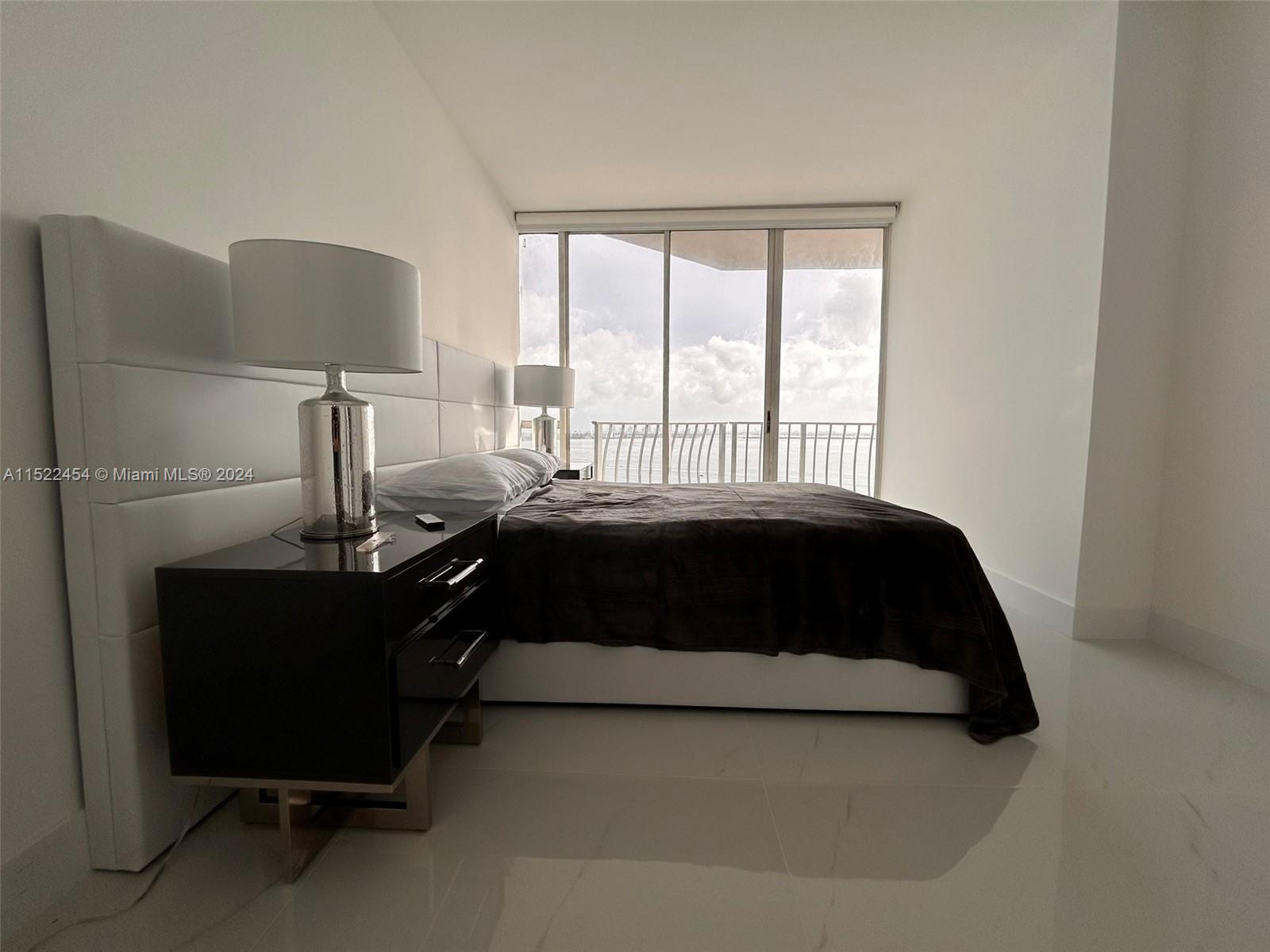 7601 East Treasure Drive, Unit PH206 North Bay Village, FL 33141 - Photo 12 of 24 a bedroom with a bed lamp and a large window