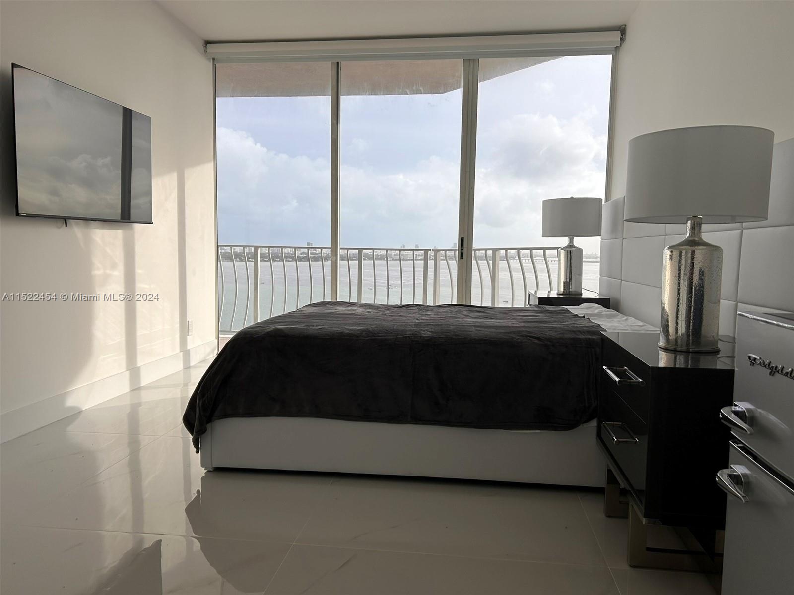 7601 East Treasure Drive, Unit PH206 North Bay Village, FL 33141 - Photo 14 of 24 a bedroom with a bed lamp and a large window