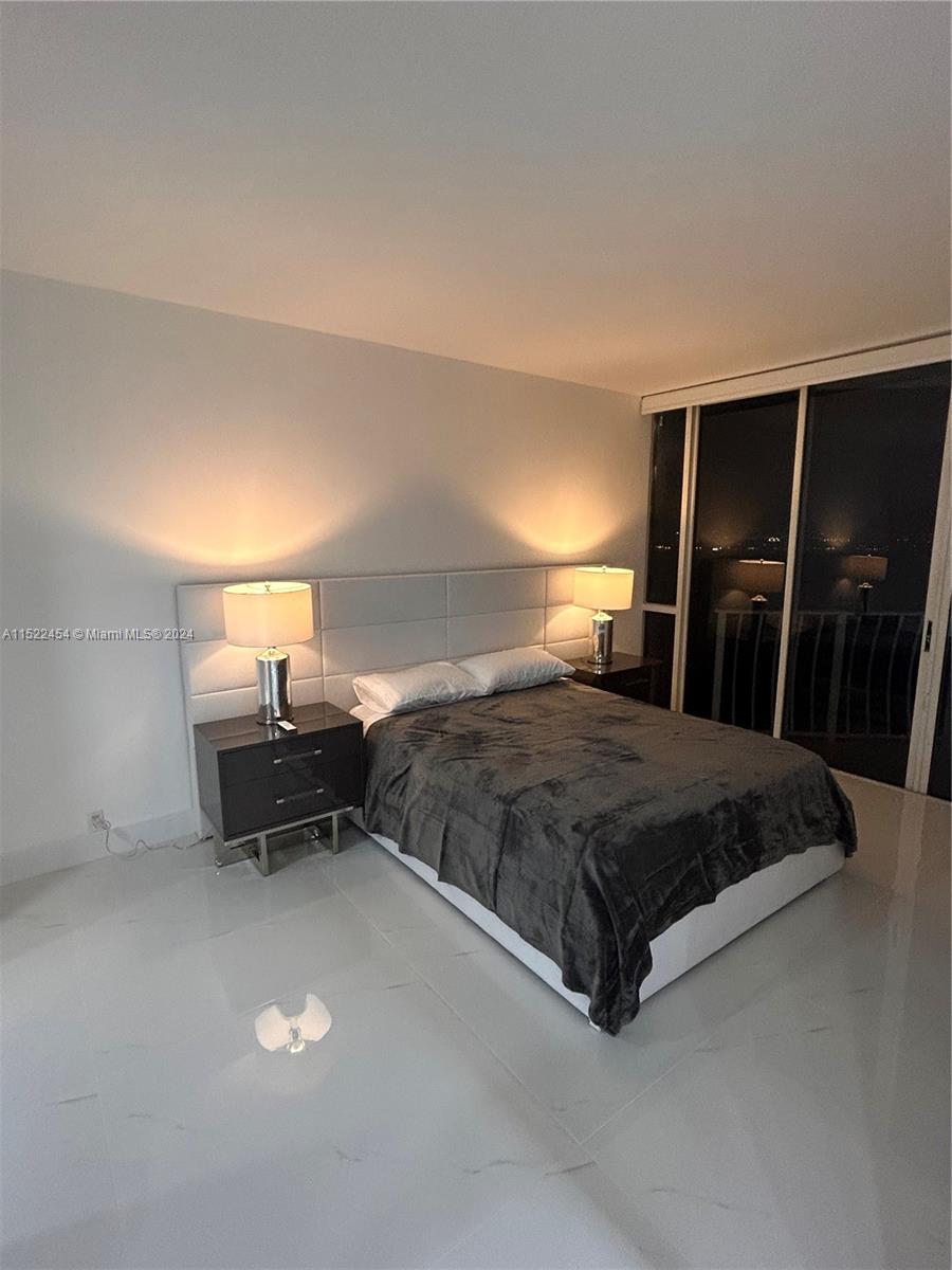 7601 East Treasure Drive, Unit PH206 North Bay Village, FL 33141 - Photo 15 of 24 a bedroom with a bed and a lamp with window