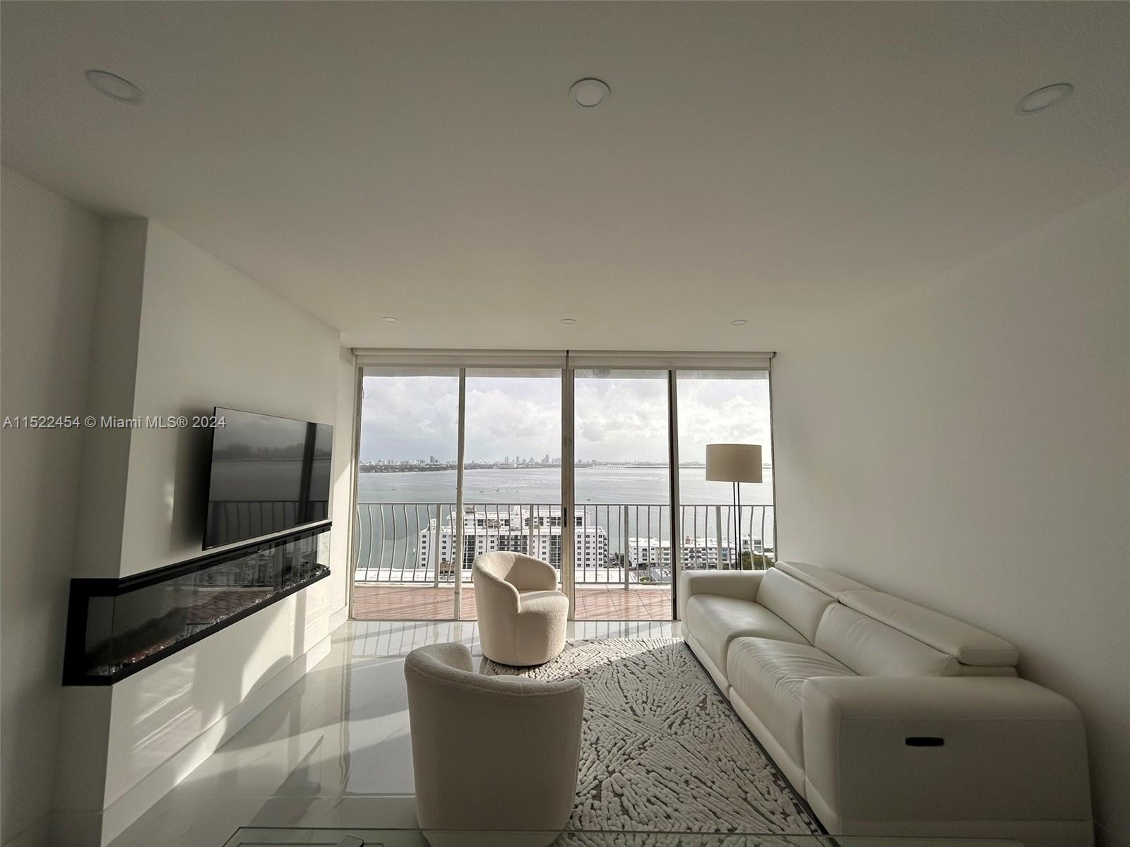 7601 East Treasure Drive, Unit PH206 North Bay Village, FL 33141 - Photo 8 of 24 a living room with furniture a flat screen tv and a floor to ceiling window