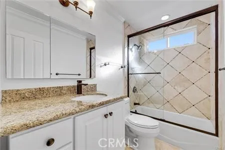 a bathroom with a granite countertop sink and a toilet