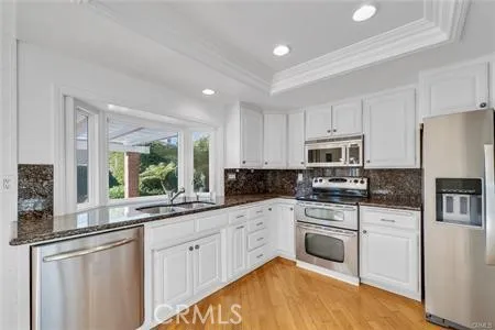 a kitchen with white cabinets appliances a sink and a window