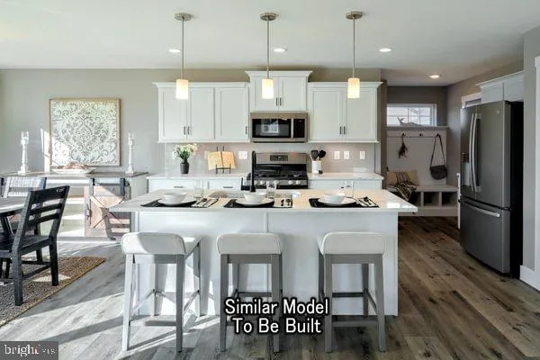 a kitchen with stainless steel appliances granite countertop a dining table chairs refrigerator and microwave