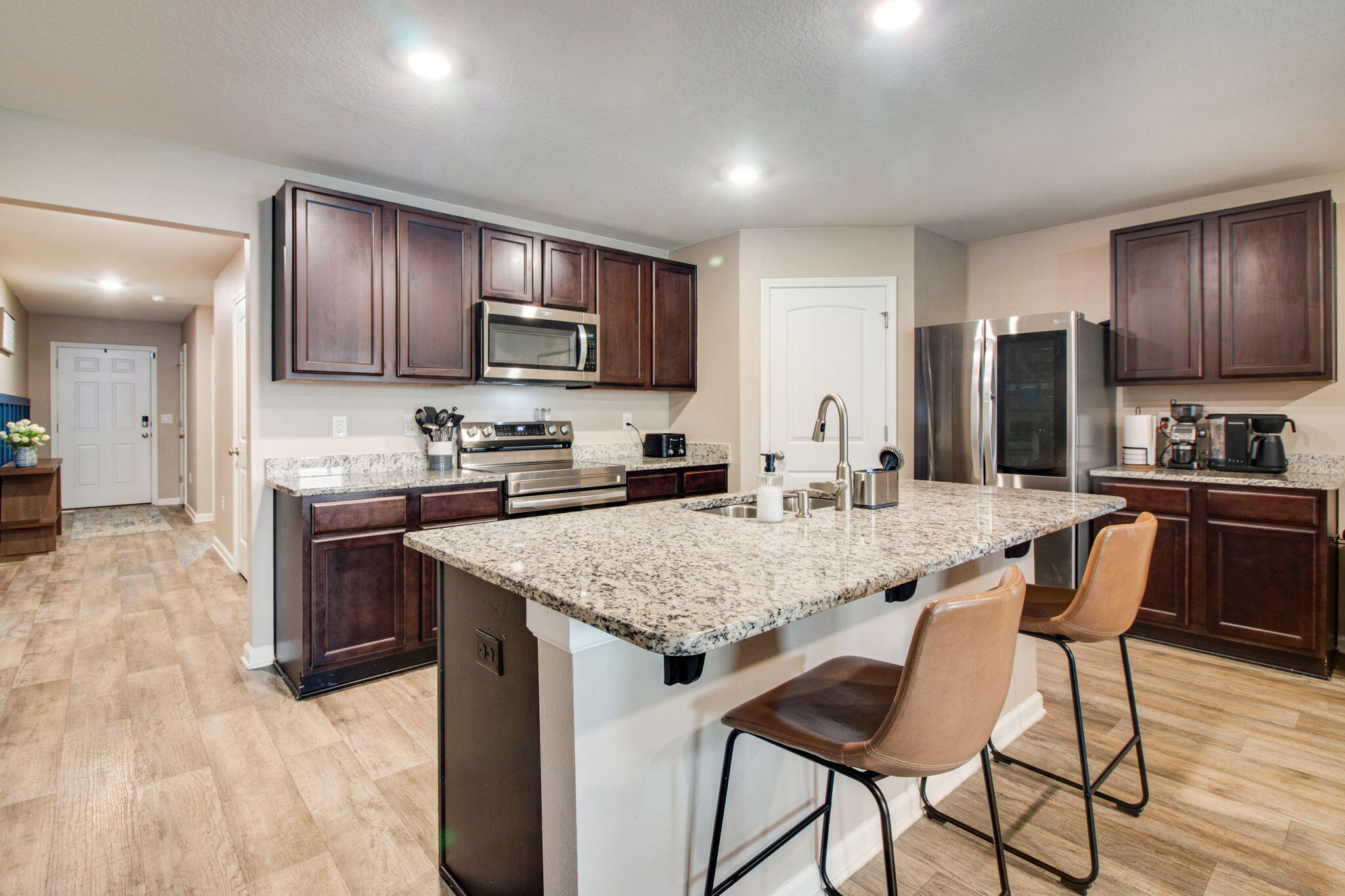 1032 Limpkin Street Crestview, FL 32539 - Photo 4 of 29 a kitchen with kitchen island granite countertop wooden cabinets a stove a microwave a island with a dining table and chairs