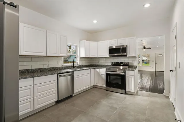 a kitchen with granite countertop white cabinets and stainless steel appliances