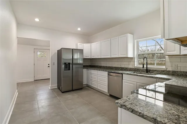 a kitchen with stainless steel appliances granite countertop a refrigerator a stove and a sink