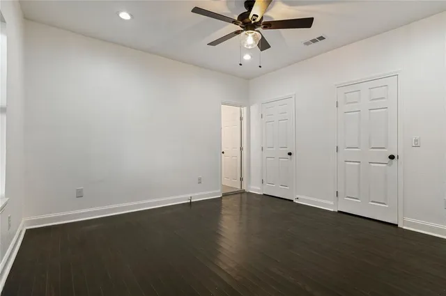 an empty room with wooden floor fan and windows