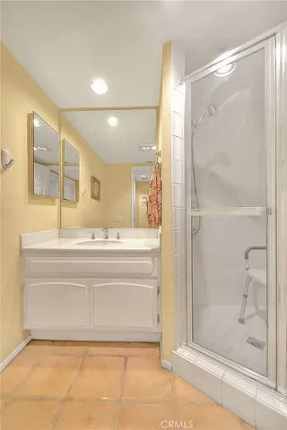 a spacious bedroom with a bed a chandelier and dresser